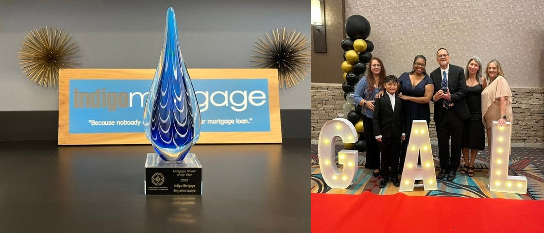 Blue glass teardrop trophy on a black surface with an Indigo Mortgage sign in the background.